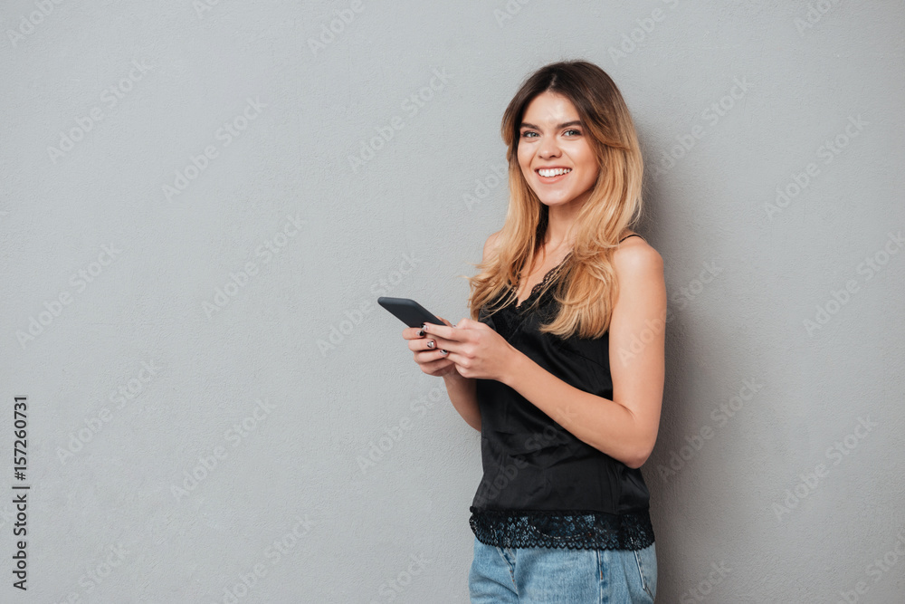 Pretty young girl holding mobile phone and looking at camera Pretty young girl holding mobile phone and looking at camera