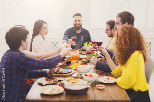 People say cheers clink glasses at festive table dinner party