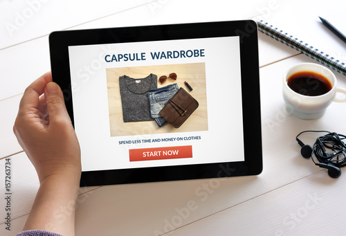 Hand holding digital tablet computer with capsule wardrobe concept on screen. All screen content is designed by me