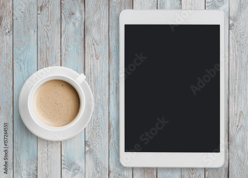 Tablet pc looking like ipad on table with coffee cup