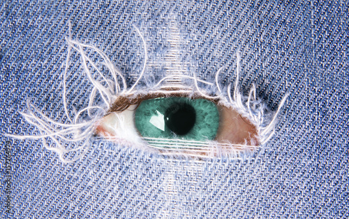 Fototapete Eye looking through ripped denim- Occhio che guarda attraverso blue jeans stracc