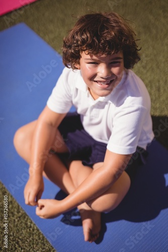 Portrait of happy schoolgirl sitting on exercise mat