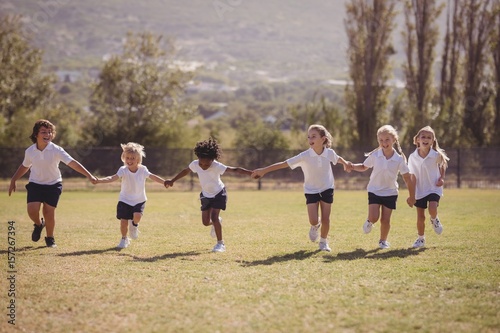 Schoolgirls running with hand in hand in park