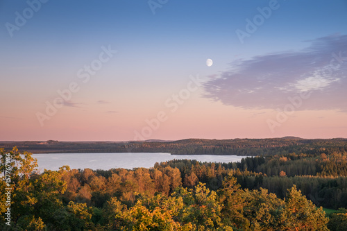 Scenic landscape with moon and sunset at autumn evening in Finland