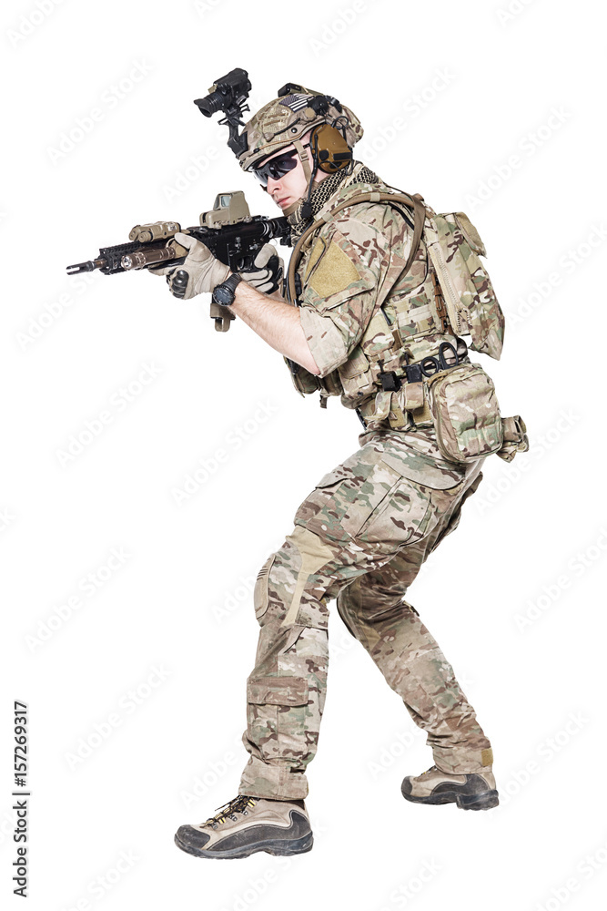 Member of US Army rangers in combat uniforms with his shirt sleeves rolled  up, in helmet, eyewear and night vision goggles, ready to firing. Low  readiness position. Studio shot, white background Stock