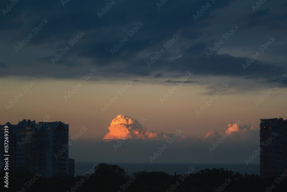 Fototapeta premium Highlighted red and orange colorful clouds during sunset in the city