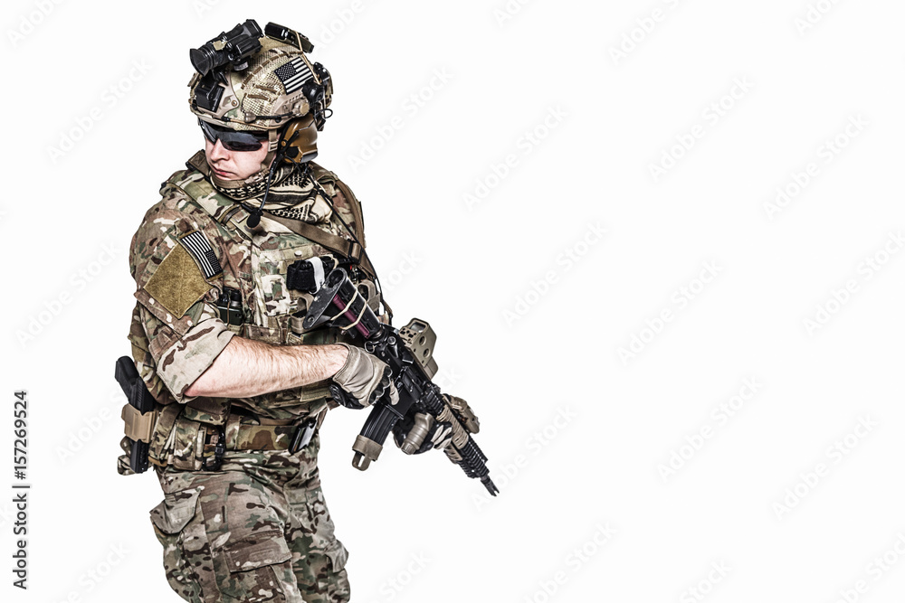 Elite member of US Army rangers in combat uniforms with his shirt sleeves rolled up, in helmet, eyewear and night vision goggles, in turning around in action. Studio shot, white background