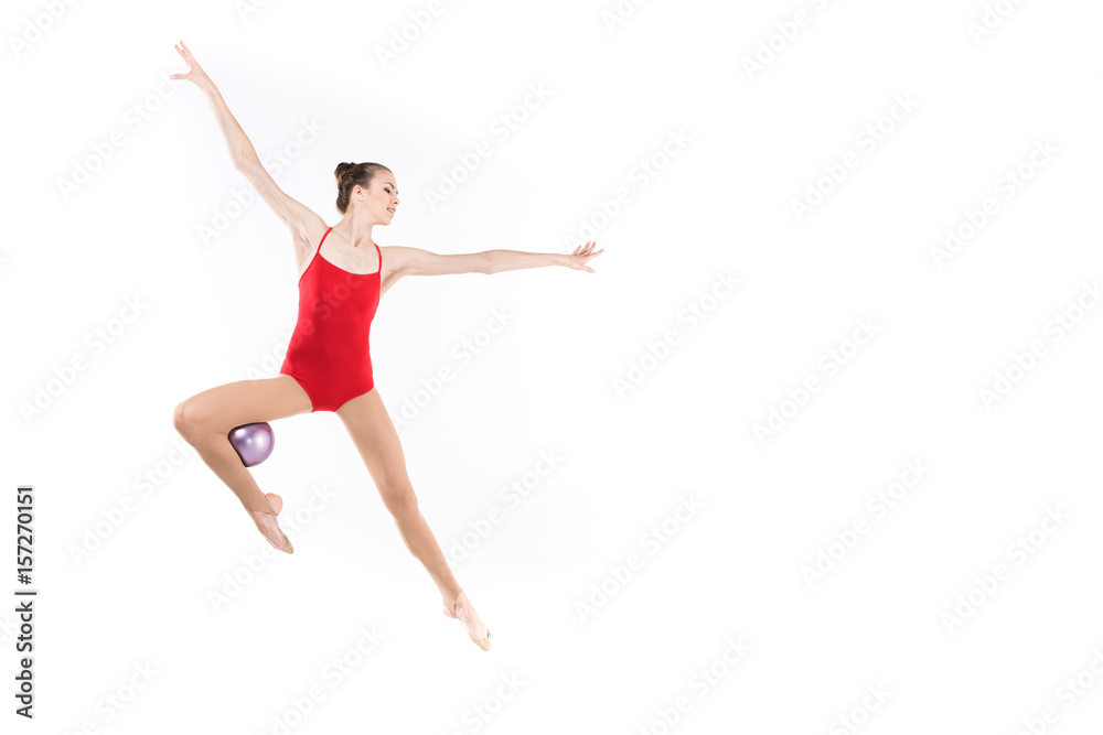 young caucasian woman rhythmic gymnast jumping with ball and looking away