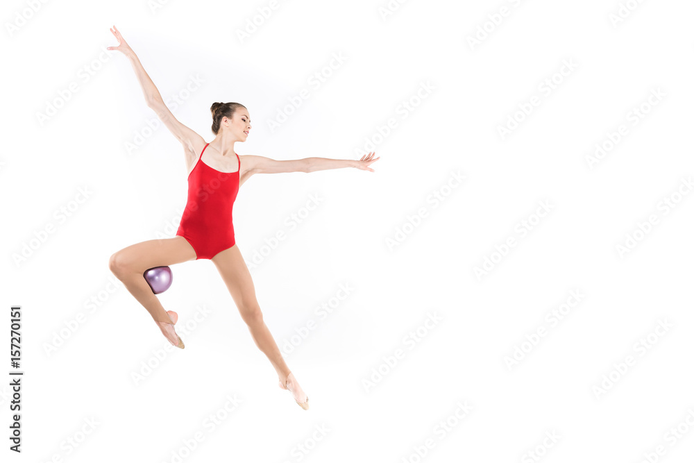 young caucasian woman rhythmic gymnast jumping with ball and looking away young caucasian woman rhythmic gymnast jumping with ball and looking away