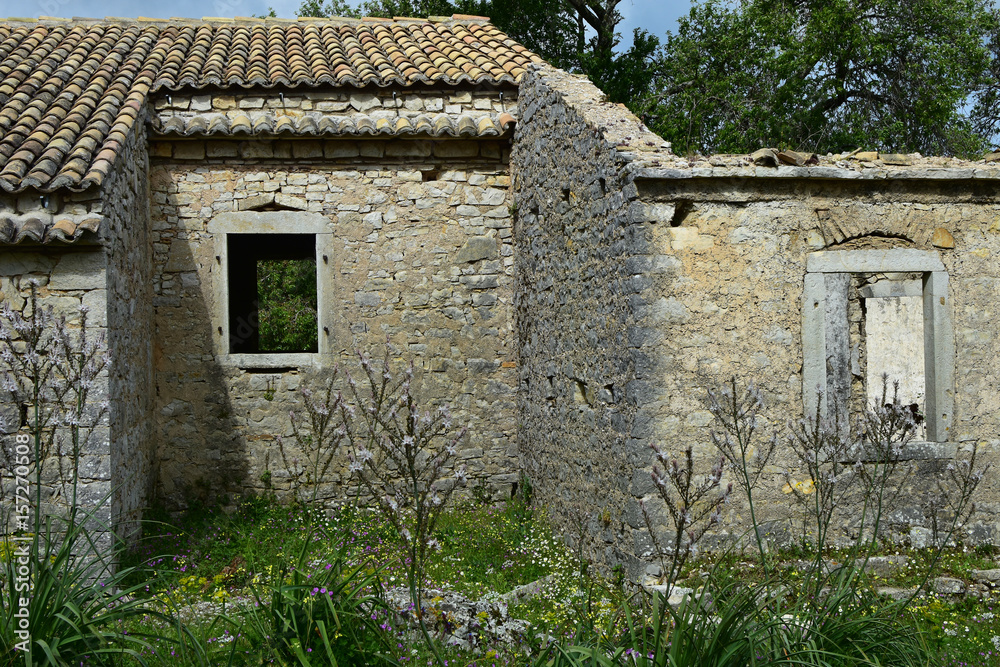 The old abandoned stone-built village of Perithia high in Pantokrator Mountain, Corfu Island, Greece. Nostalgic spring day. Clouds creep over the mountain slopes around