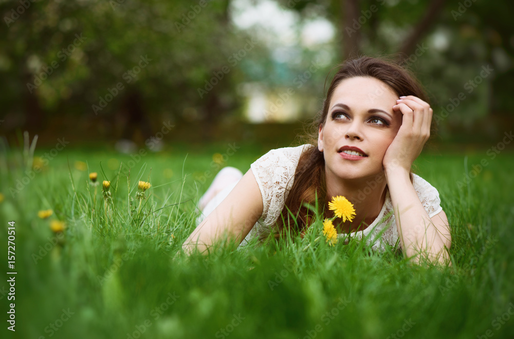 Beautiful young woman lying in green grass Beautiful young woman lying in green grass