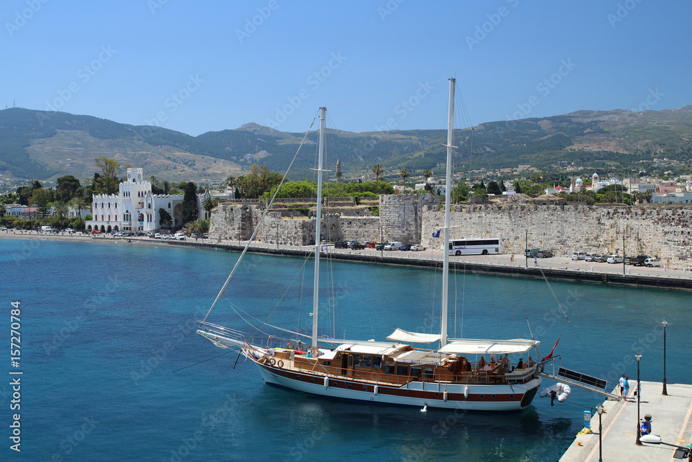 Blick auf Stadtmauer von Kos Stadt mit Holzboot und blauem Himmel und Meer
