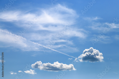 Blue sky with clouds and trail of plane