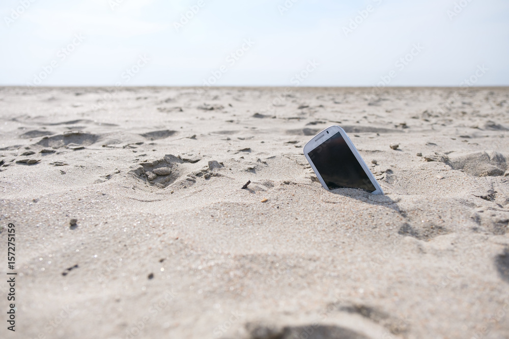 Mobile touch phone in sand on a beach Mobile touch phone in sand on a beach