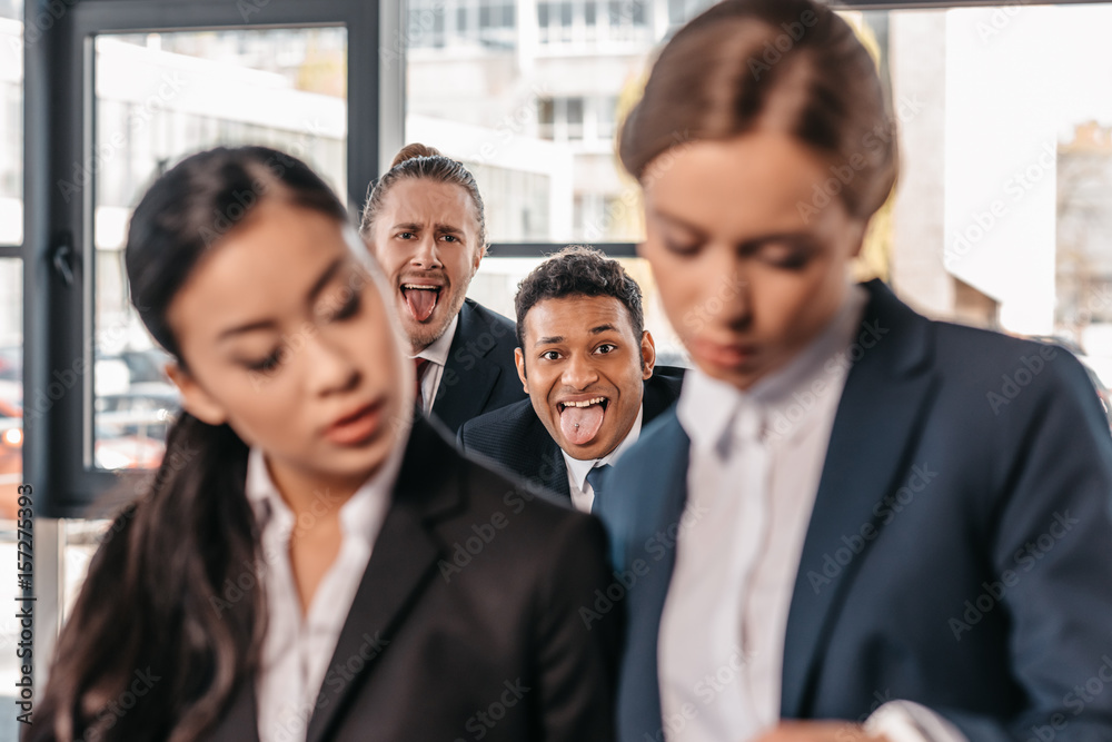 Young businesswomen working together while businessmen grimacing behind, business team working concept Young businesswomen working together while businessmen grimacing behind, business team working concept