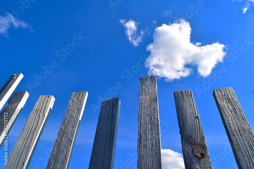 Old grungy wooden fence in Siberian village on a blue sky and clouds background