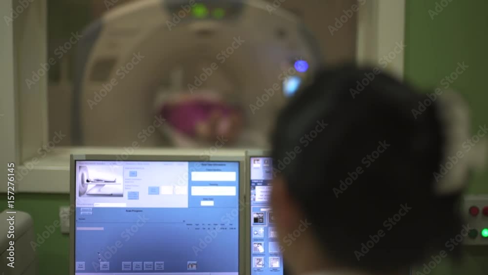 Radiology technician performs scanning in control room, crane shot, focus on the xray images of
