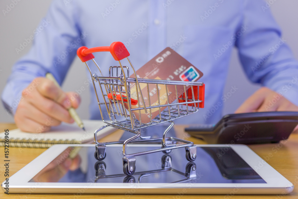 A man wrting something and shopping cart on the tablet