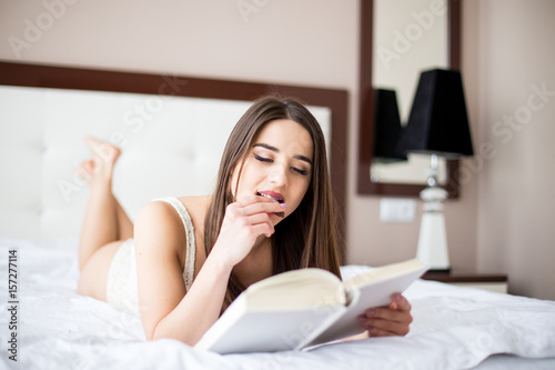 Portrait of young beautiful woman on bed , read book and eat cake in the morning
