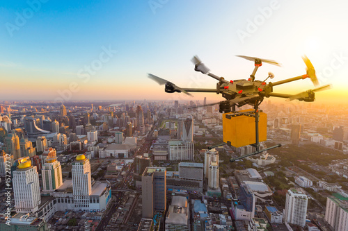 Drone transport  flying with cardboard box above city, futuristic delivery concept