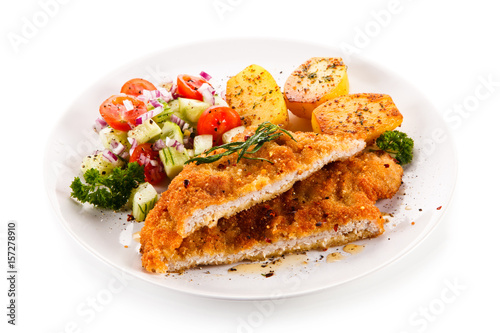 Fried pork chop with tomatoes and vegetable salad on white background