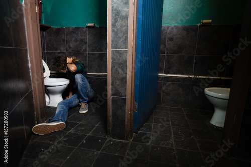 Man vomiting on toilet bowl photo