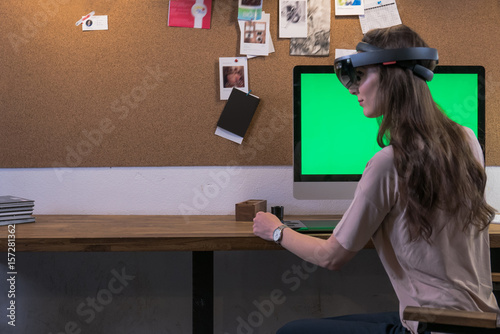 Young adult Caucasian male using holographic augmented reality glasses, creating a model on a computer screen photo