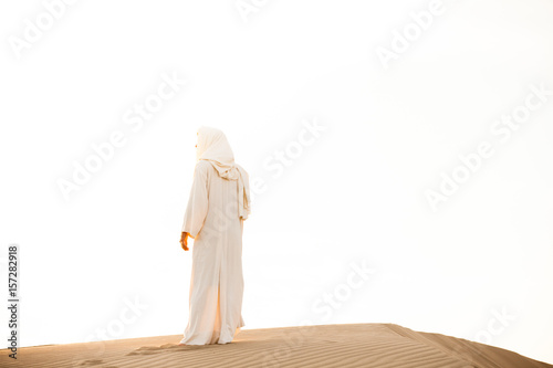 Jesus Christ watches the sunset while standing on top of a pile of sand in the sand dunes.