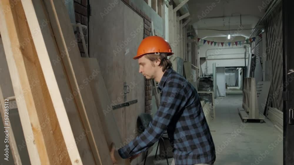 Carpenter doing his job in carpentry workshop. Man walking on factory with plywood, furniture manufacture Carpenter doing his job in carpentry workshop. Man walking on factory with plywood, furniture manufacture
