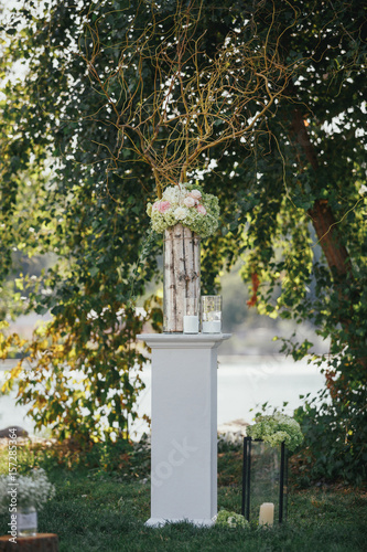 Pillar with vase and candles stands on the lawn