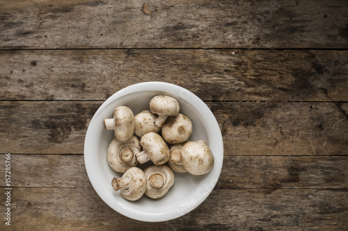 Raw mushrooms in a bowl on a wooden table