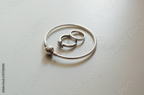 Silver bracelet, wedding rings lie on white table