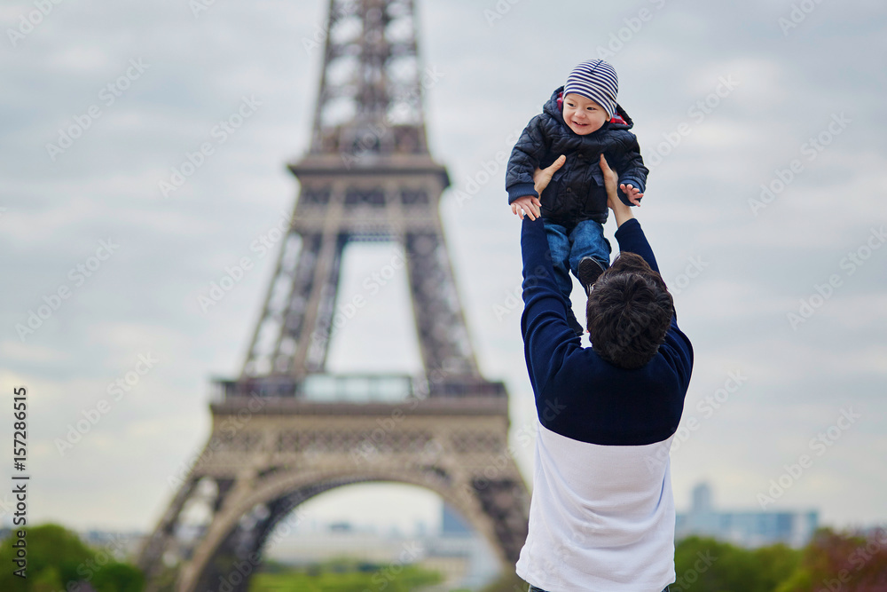 Father throwing his little son in the air near the Eiffel tower