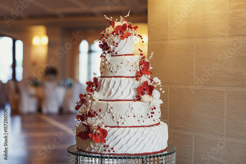 Tired wedding cake decorated with red flowers and icing