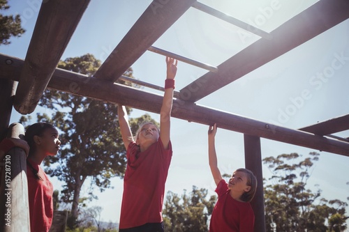 Kids climbing horizontal bars during obstacle course training