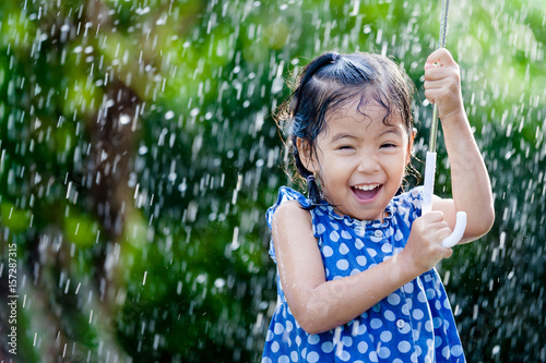 Happy asian little girl with umbrella in rain