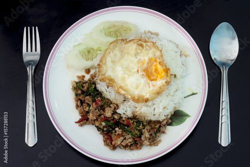 Basil Pork with Egg with Cutlery on wood black color.