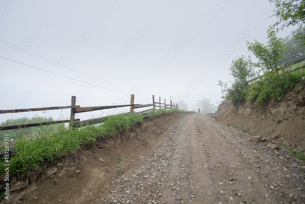 man's silhouette on mountains road in the fog