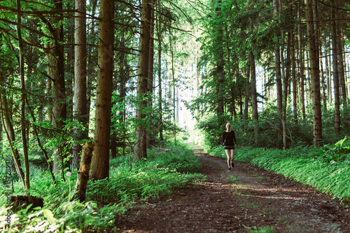 Woman running through forest in black clothes