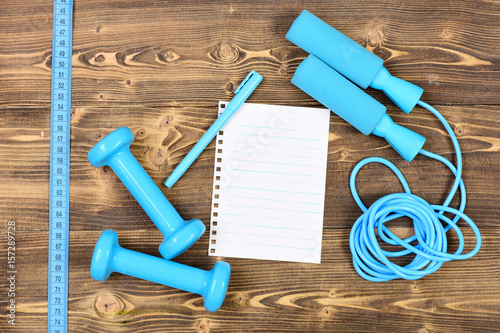 weight loss concept with notebook, skipping rope and dumbbells