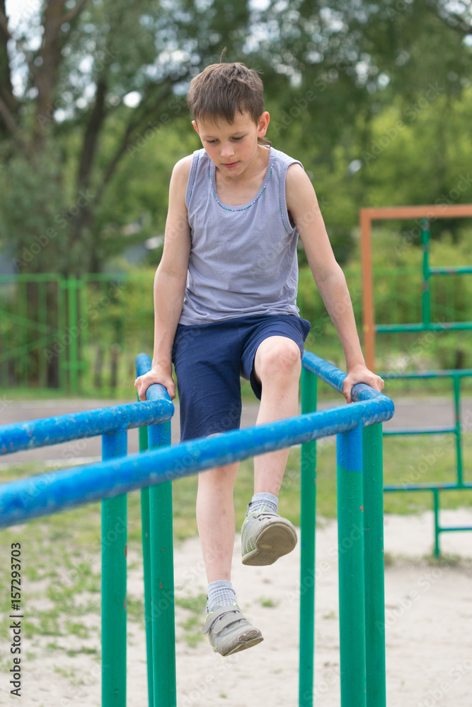 The teenager in a vest is engaged on uneven bars