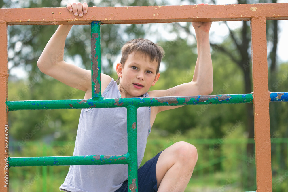 Fototapeta premium A teenager in a T-shirt is engaged in gymnastics on a horizontal bar