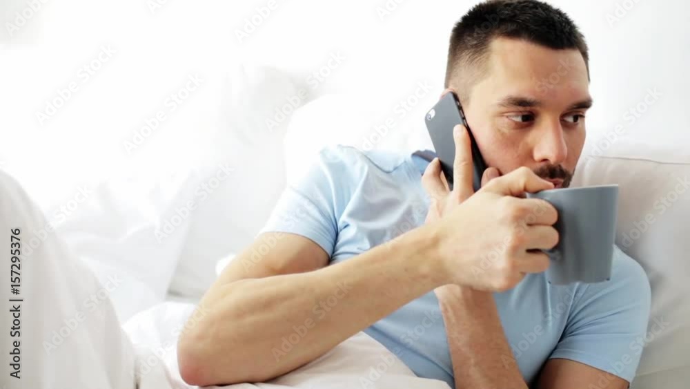 man calling on smartphone in bed at home man calling on smartphone in bed at home