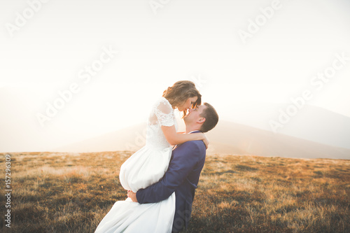 Beautiful wedding couple posing on top of a mountain at sunset