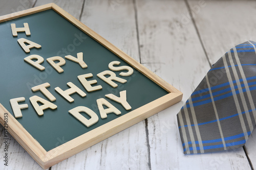 Wooden happy fathers day words on blackboard with necktie on wooden background