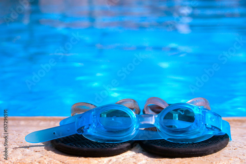 Swimming glasses and slippers by the pool
