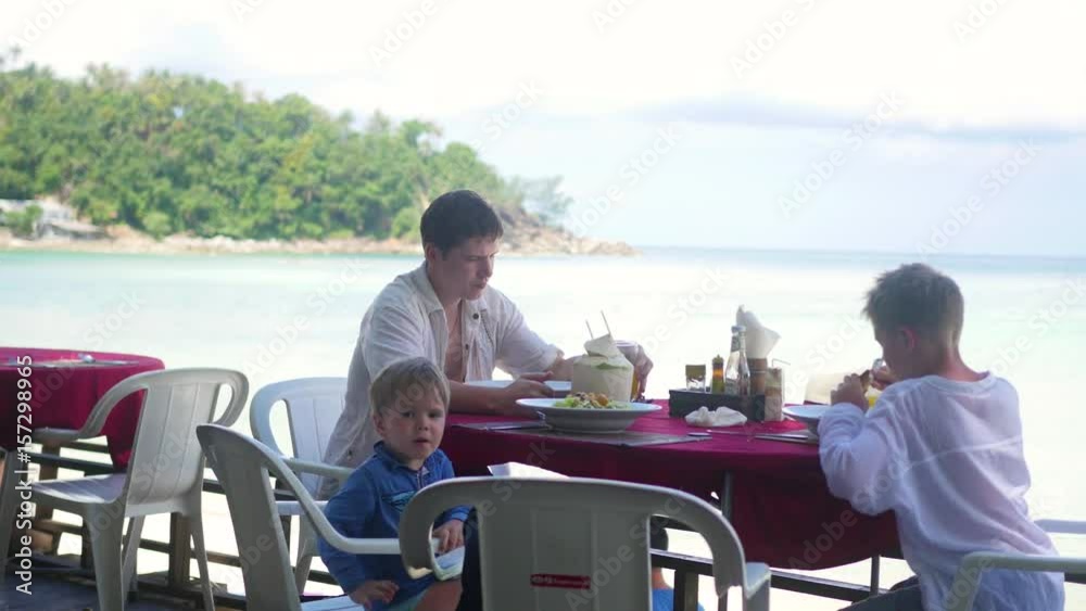 The family is dining in the restaurant on the beach.Tropical island The family is dining in the restaurant on the beach.Tropical island