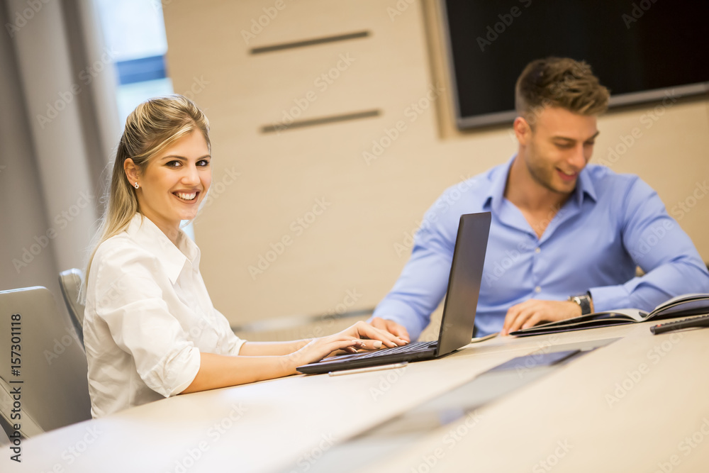 Young business people using laptop and smiling while working in office Young business people using laptop and smiling while working in office
