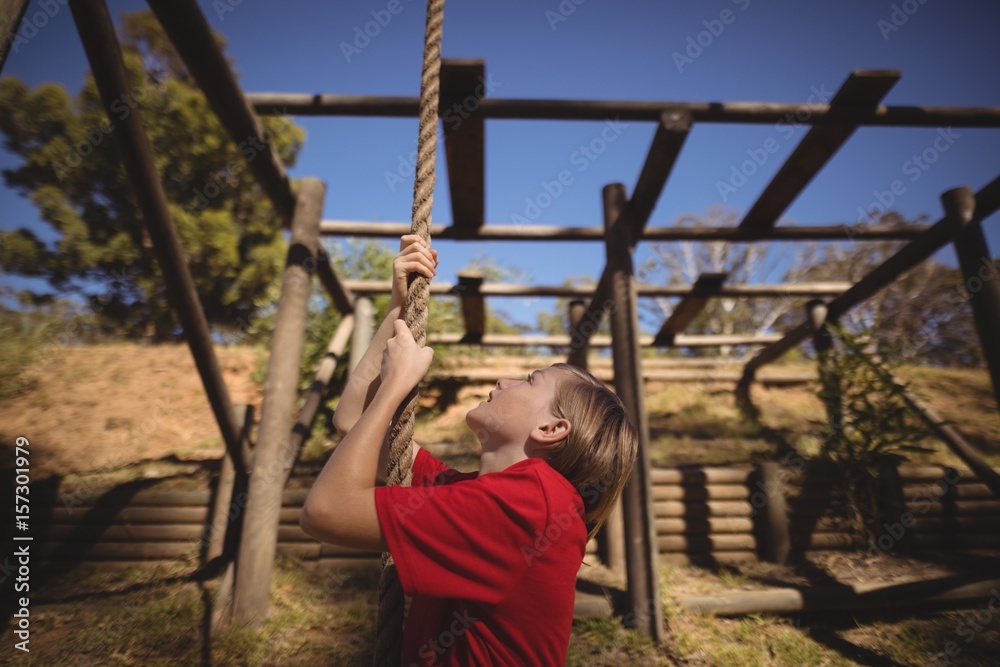Determined girl climbing rope during obstacle course Determined girl climbing rope during obstacle course