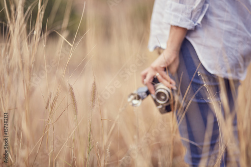 There was a woman holding a camera a retro stood as the background blur.